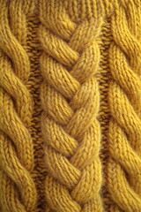 Fototapeta premium Craftsmanship in yellow wool knit showing intricate braiding pattern and texture for winter fashion design