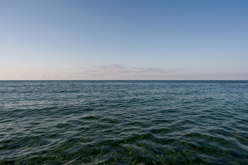 Blue sea surface with to the horizon. Sea waves with cloudy sky. Abstract background of water flow...