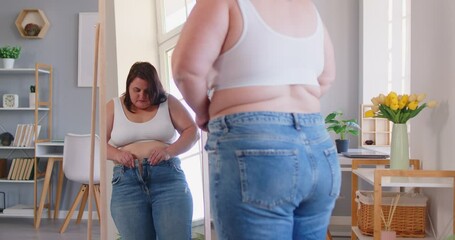 Pleasant obese woman posing in front of mirror at home, chubby overweight plus size big fat fit lady doing waist measurement with progress in weight loss after sport, dieting, looking in despair  - Powered by Adobe