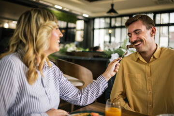 Cute couple feeding each other in a restaurant.