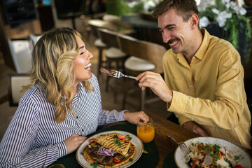 Cute couple feeding each other in a restaurant.