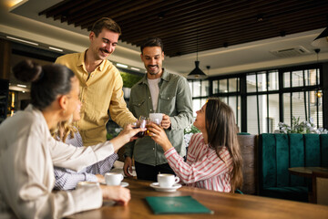 Two young men approaching a group of women at a café, engaging in friendly conversation