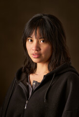 Young asian woman posing in studio with dark background