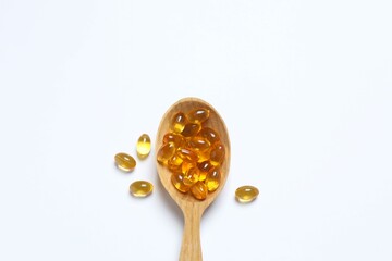 Capsule of omega 3, 6, 9 fish oil, vitamin, food supplement in wooden spoon on white background 