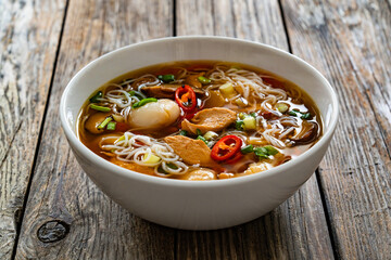 Yunnan hot pot - chinese soup with chicken meat and rice noodles on wooden table