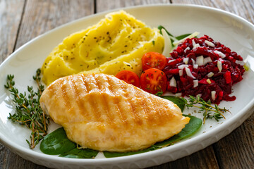 Grilled chicken breast, mashed potatoes and fresh vegetables on wooden table	