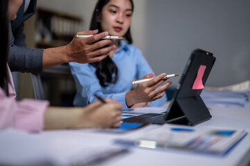 A group of people are working together at a desk with a laptop and a tablet