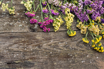 Multicolored limonium flowers on a rough wooden background. flat lay top view. copy space. rustic floral natural background. seasonal horizontal backgrounds
