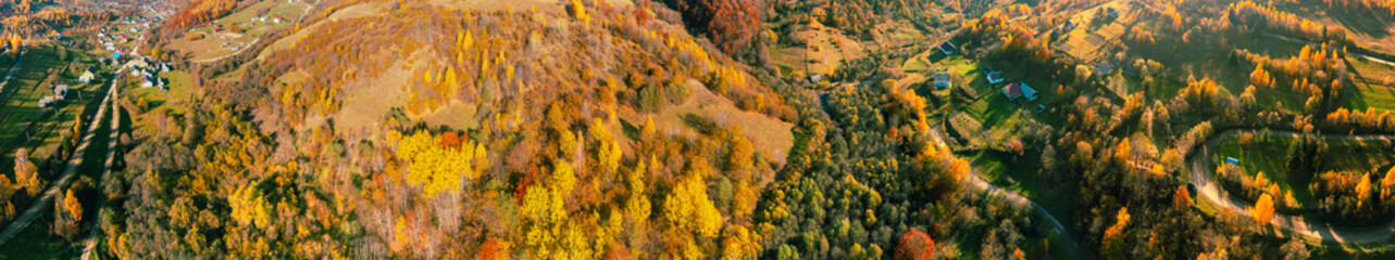 Panoramic view from above of colorful slopes of mountains on a sunny day in autumn. Beautiful landscape. Carpathian mountains, Kolochava, Ukraine. Horizontal banner