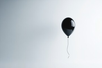 A Single Black Balloon Floats Against A White Background
