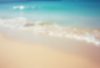 A blurred image of a beach with a clear blue ocean and sandy beach