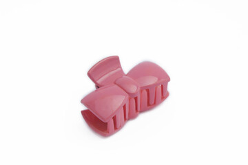 Pink plastic claw hair clip in the shape of a ribbon tie isolated on white background