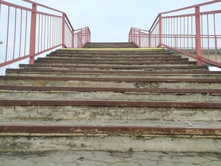 Staircase with red and yellow metal railing on the background of blue sky © Natalia