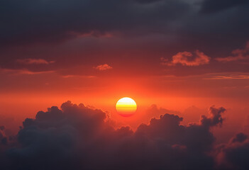 Obraz premium Dramatic orange sunset with a large sun peeking through clouds