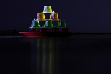 Colorful Jelly Dessert Pyramid on Dark Reflective Surface with Artistic Lighting