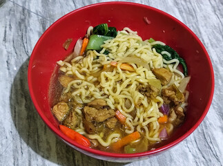 Chicken noodles with small pieces of chicken, pickles and green mustard greens.