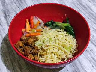 Chicken noodles with small pieces of chicken, pickles and green mustard greens.