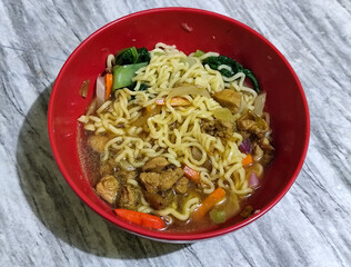 Chicken noodles with small pieces of chicken, pickles and green mustard greens.