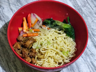 Chicken noodles with small pieces of chicken, pickles and green mustard greens.