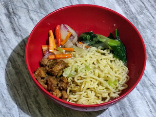 Chicken noodles with small pieces of chicken, pickles and green mustard greens.