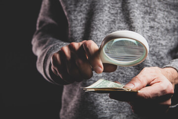 hand holding a magnifying glass of money.