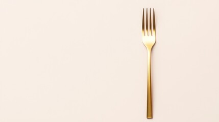 A golden fork placed on a light-colored background.