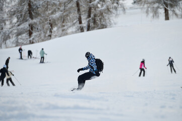 Snowboarder Gliding Down a Busy Alpine Ski Slope in Winter.