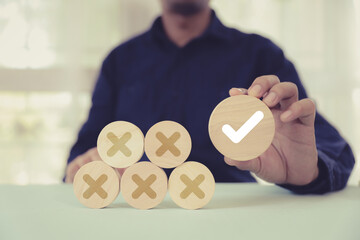 Hand choose check mark with cross symbol on wooden toy stack for true or false changing mindset or...