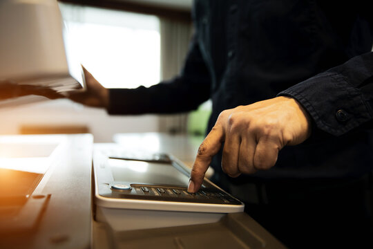 Businessman press button on control panel to use photocopy or copier or photocopier in office workplace is equipment for copy Xerox or scanner to scanning document or printer for printing paper.