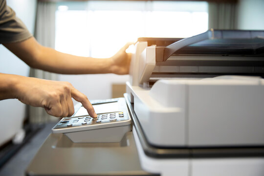 Businessman press button on control panel to use photocopy or copier or photocopier in office workplace is equipment for copy Xerox or scanner to scanning document or printer for printing paper.