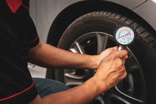 Hand car mechanic holding car tire pressure check equipment tool to checking low tire pressure inflating tires to or refill or air inflate to safety and car care service maintenance inspection.