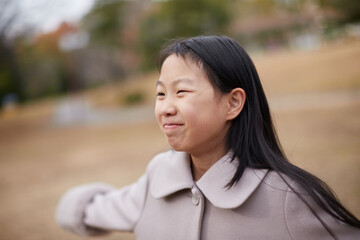 冬の朝の公園で元気で楽しく遊んでいる小学生の女の子の様子