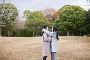 Fototapeta premium 冬の朝の公園で元気で楽しく遊んでいる子供姉妹の姿