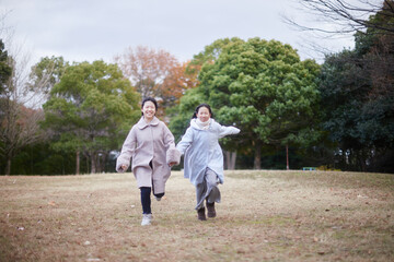 Naklejka premium 冬の朝の公園で元気で楽しく遊んでいる子供姉妹の姿