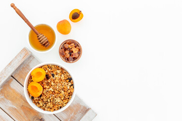 Bowl with oatmeal granola and ingredients - apricots and honey. Top view