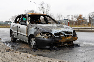 Burnt passenger car standing on the road. Vehicle with interior largely burned out.
