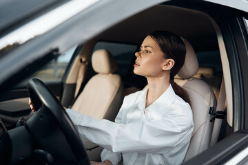Woman driving car, hand on steering wheel a woman seated in the driver's seat of a car, her hand...