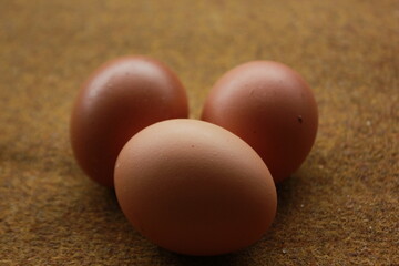 three chicken eggs on a brown carpet