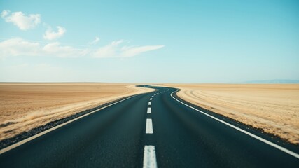 Fototapeta premium Asphalt road curving through a desolate, sandy landscape under a clear sky, symbolizing journey and adventure