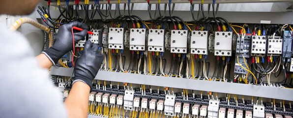 Electrical technician checking circuit breaker power electricity on switchboard cabinet for service...