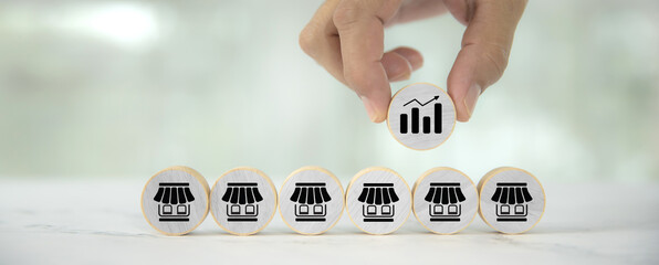 Hand choose graph on wooden toy stack in pyramid with franchise business store for franchising to...