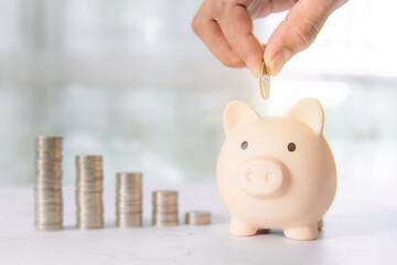 Hand holding coin in saving piggy bank with coins stack in graph for save or money savings plan...