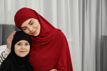 Muslim woman and her daughter spending time together at home, space for text