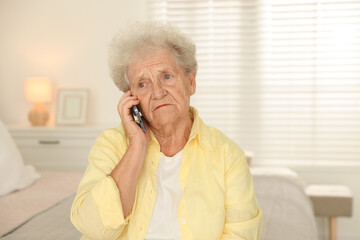 Senior woman talking on smartphone at home