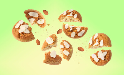 Yummy nut cookies with almond petals in air on green yellow gradient background
