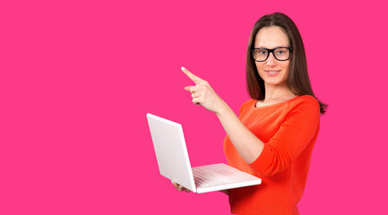 Naklejka premium Clever brunnette woman programmer or sociale media manager holding in hands laptop isolated pink color background. Online education. Showing a finger up. Online shopping.