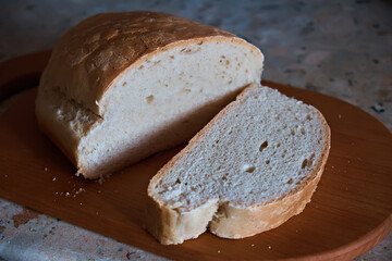 Sliced piece of fresh rustic bread on a kitchen board. Selective focus