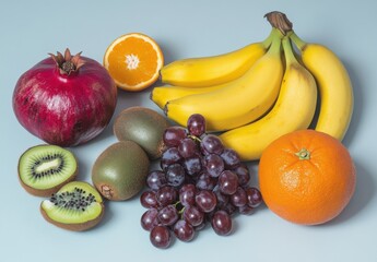 Colorful Assortment of Fresh Fruits Including Bananas, Grapes, Kiwi, Pomegranate, and Oranges Arranged on a Soft Blue Background for Healthy Eating Concept