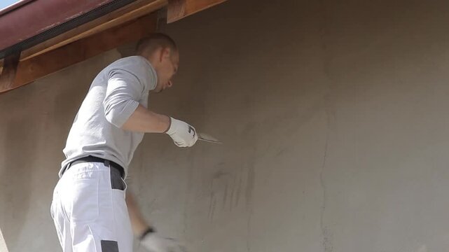 construction worker applying plaster under roof