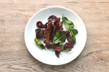 fried crispy salty fermenting beef meat with lemon leaf and chili on plate 